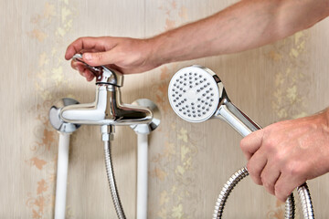 Wall Mural - Plumber connected showerhead with flexible hose to single lever faucet in bathroom.