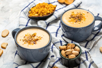 Wall Mural - Two bowls of cream of corn soup with pistachios and croutons on top, vertical image, Vegan cuisine. Restaurant menu, dieting, cookbook recipe