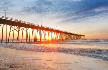 Wall Mural - Kure Beach Fishing Pier at sun rise with colorful clouds, Kure Beach, North Carolina, USA. Kure beach is the home to the oldest fishing pier on the Atlantic Coast and an oceanfront park.