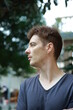 © Kutyar - Red haired european guy with freckles on his face and arms and body in the garden posing and looking around