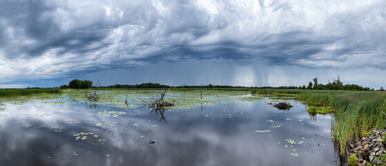 Wall Mural - scenic landscape of stormy rain clouds reflecting on a large pond on a summer day