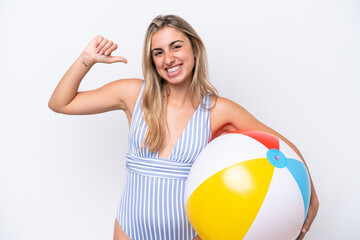 Wall Mural - Young caucasian woman holding beach ball isolated on white background proud and self-satisfied