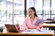 © David - Asian Businesswoman working in the workspace, doing report analyzing financial figures on a graph in tablet and sitting on laptop computer