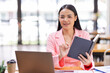 © David - Asian Businesswoman holding notes and working on a laptop computer in the workplace, doing document planning analyzing the financial report, business plan investment, finance analysis concept.