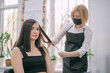 © Anna - Professional hairdresser woman in an apron makes a haircut to a young girl in a beauty salon.