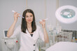 © Anna - Portrait of a young beautiful woman beautician in a medical white uniform in her office with cosmetology equipment
