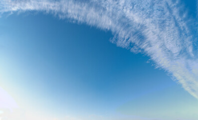 Wall Mural - cirrus clouds in a bow over blue sky background