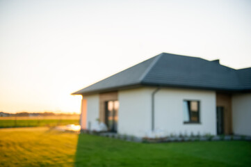 Blurred view of beautiful house with green lawn on sunny day