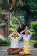 © Odua Images - balinese hindu couple put their hand on top of their head while doing the prayer at pura in the morning