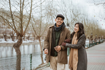 happy couple enjoying their time together walking near a river in winter