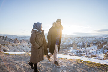 Wall Mural - asian muslim couple romantic while enjoying the view of beautiful cappadocia in snow during winter