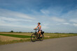 A young lady riding her bicycle on a cycle path through very typical Dutch countryside in the Netherlands on a clear sunny summer day. Example of uniform precision farming can be seen behind