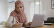 © ChayTee - Young Gen Z workforce islam woman self learn MBA online class reskill upskill job at home. Asia people arab girl study relax sit at table wear hijab scarf write or typing e-mail work on digital laptop