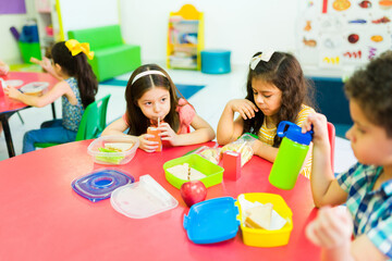 Wall Mural - Preschool children eating a sandwich and drinking juice for lunch