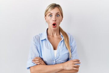 Poster - Beautiful blonde woman standing over white background afraid and shocked with surprise expression, fear and excited face.