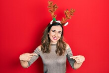 Young Hispanic Girl Wearing Deer Christmas Hat Looking Confident With Smile On Face, Pointing Oneself With Fingers Proud And Happy.