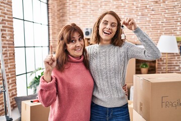 Sticker - Mother and daughter moving to a new home holding keys smiling with an idea or question pointing finger with happy face, number one