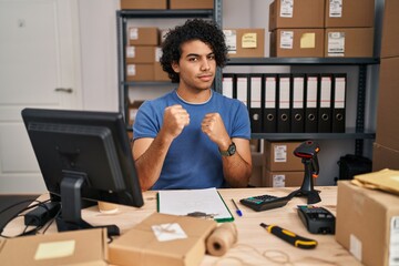 Poster - Hispanic man with curly hair working at small business ecommerce ready to fight with fist defense gesture, angry and upset face, afraid of problem