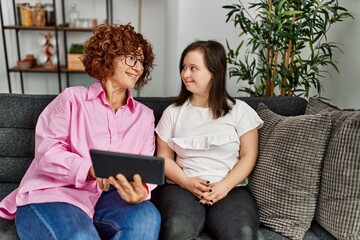 Wall Mural - Mature mother and down syndrome daughter at home using touchpad device