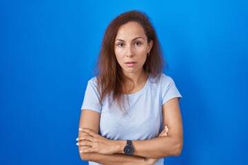 Canvas Print - Brunette woman standing over blue background looking sleepy and tired, exhausted for fatigue and hangover, lazy eyes in the morning.