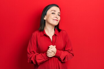 Wall Mural - Middle age hispanic woman wearing casual clothes with hands together and crossed fingers smiling relaxed and cheerful. success and optimistic