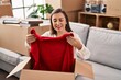 © Krakenimages.com - Middle age woman unpacking cardboard box sitting on sofa at new home
