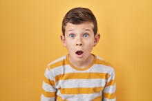 Young Caucasian Kid Standing Over Yellow Background Afraid And Shocked With Surprise Expression, Fear And Excited Face.