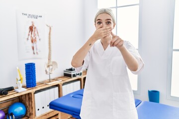 Sticker - Young caucasian woman working at pain recovery clinic laughing at you, pointing finger to the camera with hand over mouth, shame expression