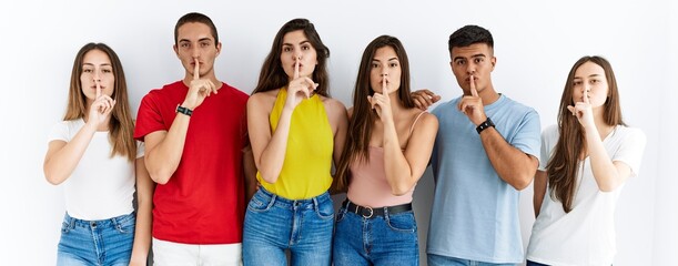 Canvas Print - Group of people wearing casual clothes standing over isolated background asking to be quiet with finger on lips. silence and secret concept.