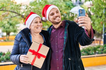 Mother and son make selfie by the smartphone holding christmas gift at park