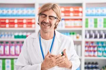 Poster - Caucasian man with mustache working at pharmacy drugstore smiling with hands on chest with closed eyes and grateful gesture on face. health concept.