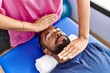 © Krakenimages.com - Man and woman wearing physiotherapist uniform having reiki session at physiotherpy clinic