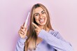 © Krakenimages.com - Beautiful hispanic woman holding electric toothbrush smiling happy pointing with hand and finger