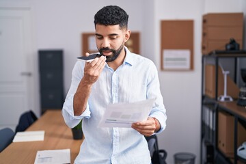 Sticker - Young arab man business worker talking on smartphone reading document at office