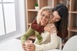 © Krakenimages.com - Two women mother and daughter hugging each other drinking coffee at home