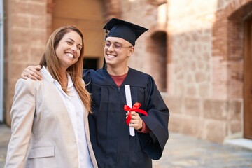 Man and woman mother and son hugging each other celebrating graduation at university