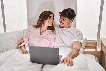 Poster - Mand and woman couple using laptop sitting on bed at bedroom