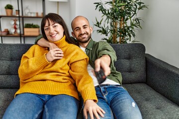 Wall Mural - Young hispanic couple smiling happy watching movie sitting on the sofa at home.