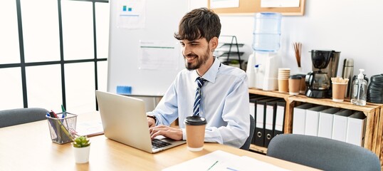 Wall Mural - Young hispanic businessman smiling happy working at the office.