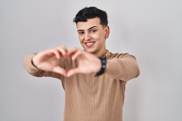 Sticker - Non binary person standing over isolated background smiling in love doing heart symbol shape with hands. romantic concept.