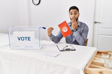 Sticker - Young handsome man with beard at political campaign election holding tunisia flag covering mouth with hand, shocked and afraid for mistake. surprised expression