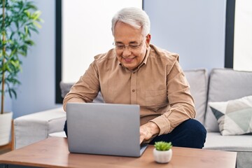 Poster - Senior man using laptop sitting on sofa at home