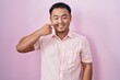 © Krakenimages.com - Chinese young man standing over pink background pointing with hand finger to face and nose, smiling cheerful. beauty concept