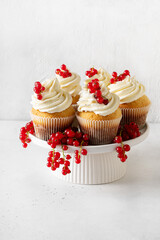 Wall Mural - Vanilla cupcakes with red currant berries on plate on white