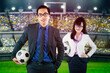 Two business people holding soccer ball in stadium