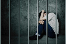 Sad Man Sitting Behind Bars In The Jail