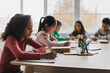 © Prostock-studio - African Schoolgirl Taking Notes Sitting With Diverse Classmates In Classroom