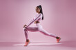© gstockstudio - Beautiful young woman in sports clothing doing stretching exercises against pink background