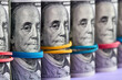 A row of rolled hundred dollar bills with rubber bands on purple background