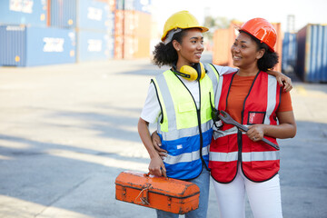 young female African factory workers or engineer holding tool box and wrench in containers warehouse storage